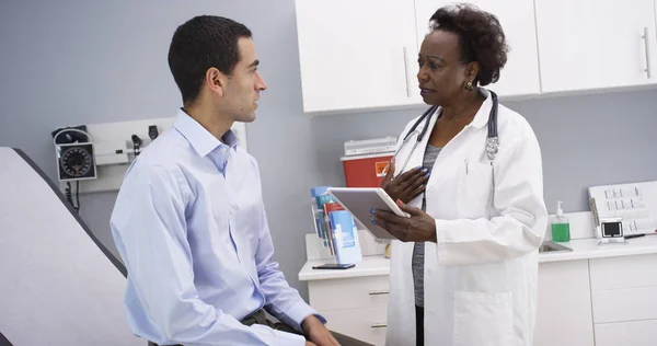 African senior medical doctor using elctronic notebook to take notes of patient