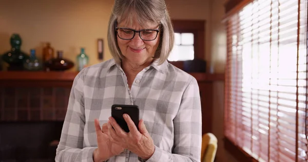 快乐的老年人在她家里用手机用窗户发短信 — 图库照片
