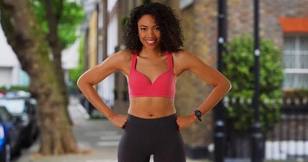 Portrait of black woman athlete in active wear looking at camera laughing