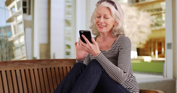 Kaukasische Vrouw Senior Gebruikend Mobiel Apparaat Zittend Bank Door Modern — Stockfoto