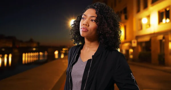 Pretty African American Millennial woman standing outdoors in Florence at night