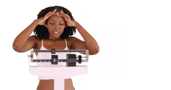 不快乐的年轻黑人妇女站在体重秤上的工作室与复制空间 — 图库照片