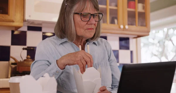 老婦人のキッチンでポータブル コンピューターを使用している中華料理を食べる — ストック写真