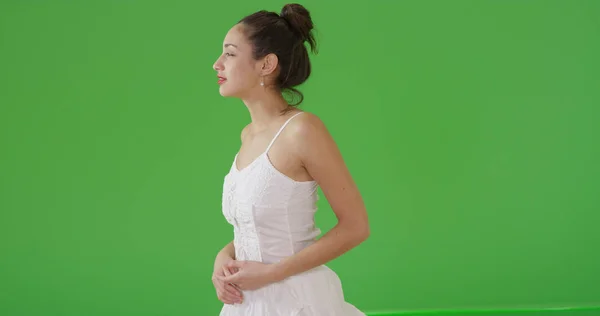 A Latina woman looking off into distance in her sundress on green screen
