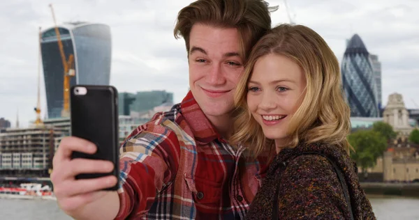 スマート フォンで Selfie を取って都会で陽気な若いカップル — ストック写真