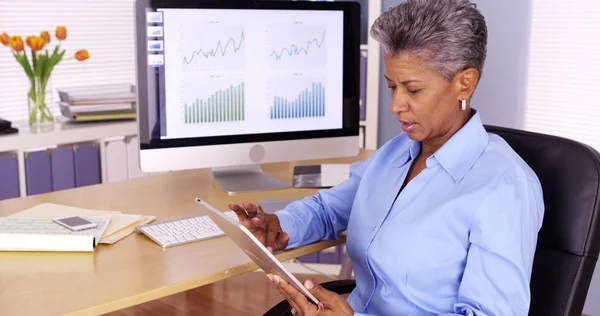 Executive senior black businesswoman working on tablet at desk