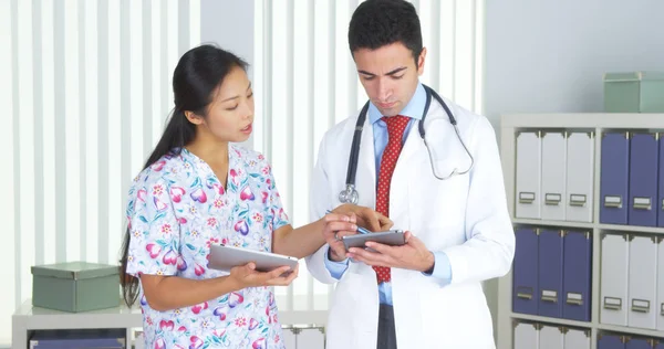 Médico Hispânico Conversando Com Enfermeira Asiática Com Comprimidos — Fotografia de Stock