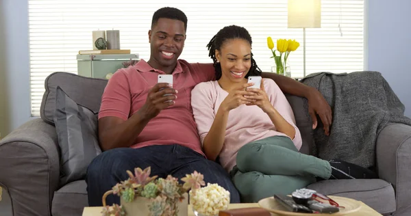 Gelukkige Jonge Zwarte Paar Ontspannen Bank Met Behulp Van Smartphones — Stockfoto