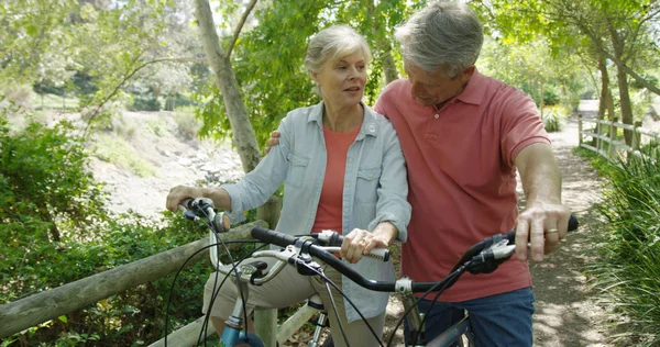 Elderly white couple talking outdoors on bikes