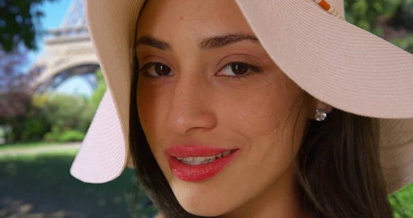 可爱的西班牙裔女性在时尚的帽子微笑着对着埃菲尔铁塔附近的相机 — 图库照片