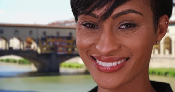 混血女性フィレンツェ ヴェッキオ橋近くのカメラに笑顔で旅行 — ストック写真