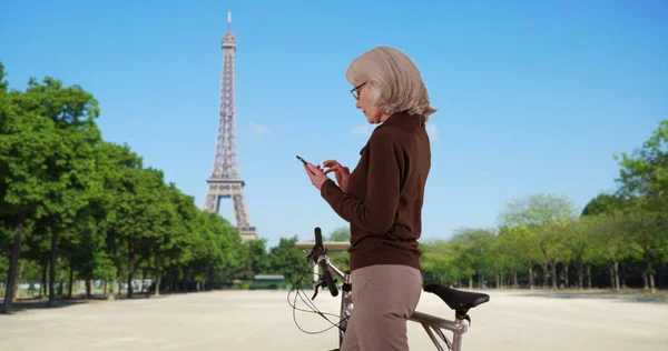 Ältere Frau Mit Fahrrad Sms Auf Handy Vor Dem Eiffelturm — Stockfoto