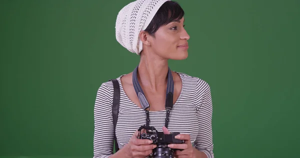 Black millennial woman with camera on green screen