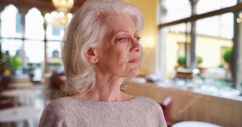Close up of sad older woman standing in banquet hall or restaurant