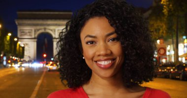 Neşeli Afrikalı kadın mutlu Caddesi Arc de Triomphe yakınlarında kamera bakıyor