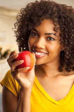 Genç Afrikalı kadın güleryüzlü ve holding elma kapalı ev mutfak yakın çekim