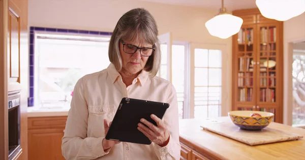 White Mature Lady Using Pad Device Indoors Domestic Kitchen Setting — Stock Photo, Image