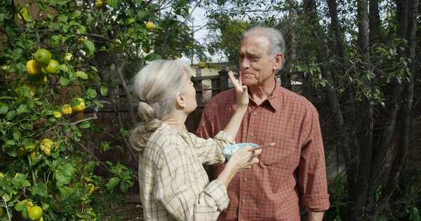 Senior couple standing eating in garden