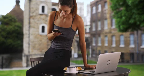 Young business woman with coffee multitasking texting and working on laptop