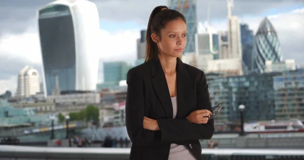 millennial business woman in black sport coat crossing arms with London Skyline