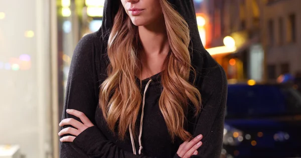 Blonde female wearing a hoodie outside at night