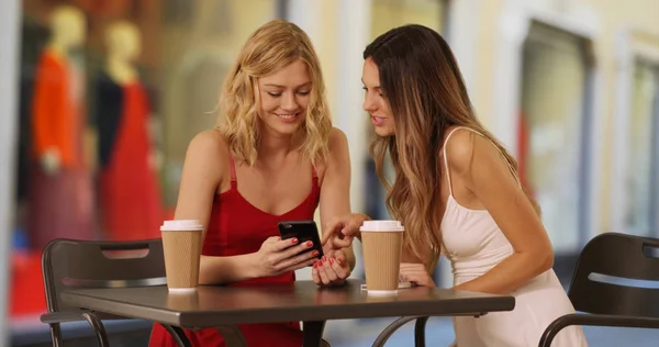 Hermosas Mujeres Jóvenes Mirando Teléfono Inteligente Mientras Chismorrean Cerca Tiendas — Foto de Stock