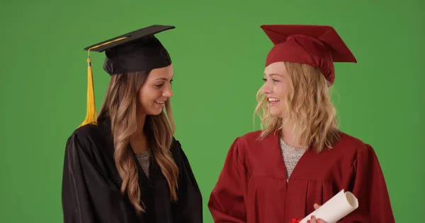 两个美丽的女学生在绿色屏幕上大学毕业 — 图库照片