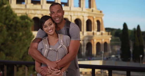 Black man and woman pose tenderly together near Colosseum in Rome