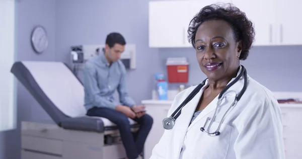 Close up of African doctor looking at camera while male patient waits