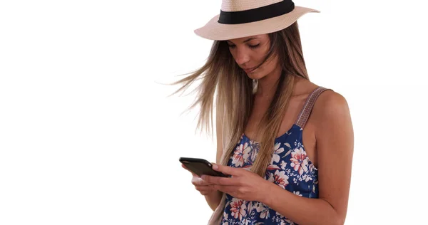 Millennial girl in romper and fedora texting on phone on white copy space