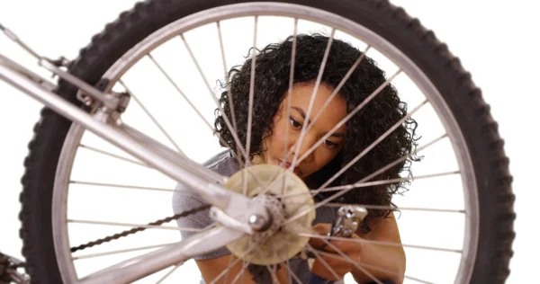 Young focused African lady on white copy space repairing bicycle alone