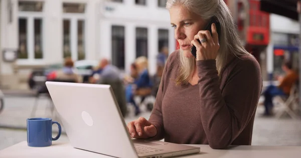 Zaneprázdněný Starší Bílá Žena Pracuje Notebooku Dělá Telefonní Hovor Kavárně — Stock fotografie