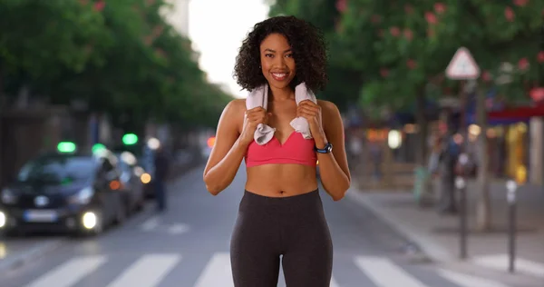 Black woman athlete on city street in active wear with towel around her neck