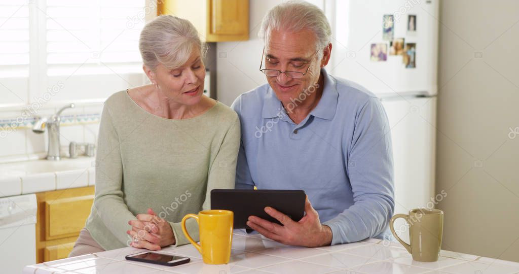 Senior couple using tablet pad in kitchen