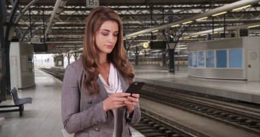 Tren istasyonunda taşınabilir aygıtta ileti gönderme iyi giyimli Bayan