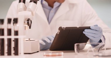 Bin yıllık Latino tıbbi bilim adamı tablet bilgisayar kullanarak laboratuvar