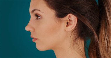 Genç beyaz kadının deniz mavisi zemin üzerine yalnız yan görünümü Kapat