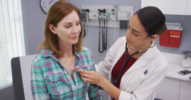 Güzel genç latina Doktor stetoskop üst düzey hastalar hayati incelemek için kullanarak