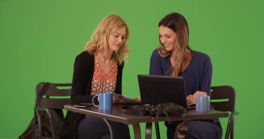 İki kadın harita ve dizüstü café'de yeşil ekran üzerinde hedef almak için kullanma