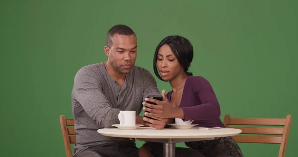 在绿色屏幕上的咖啡店使用手机的愉快的黑人夫妇 — 图库照片