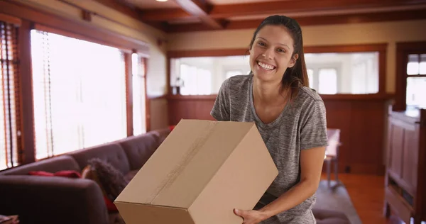 Joyful young woman in home carrying shipping box ready to deliver