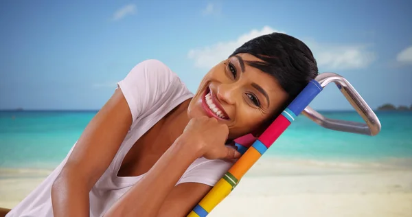 坐在加勒比海海滩海洋旁的年轻黑人女性与镜头交谈 — 图库照片