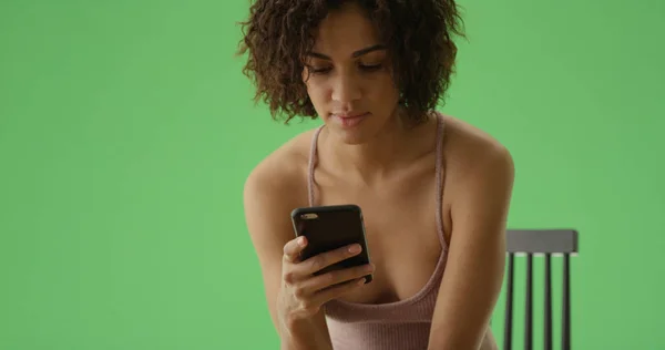 一个年轻的非洲裔美国女孩在绿色屏幕上阅读智能手机上的文字 — 图库照片