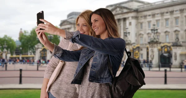 Couple of attractive white females traveling in London take selfie on smartphone