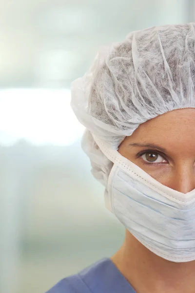 Close up portrait of serious young woman doctor in scrubs with mask and cap