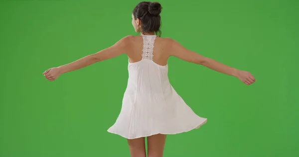 一个拉丁女孩在绿色的屏幕上旋转她的太阳裙 — 图库照片
