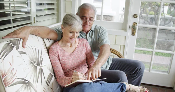 Senior couple sitting and writing in journal