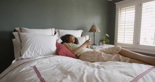 Young beautiful black woman in bed texting