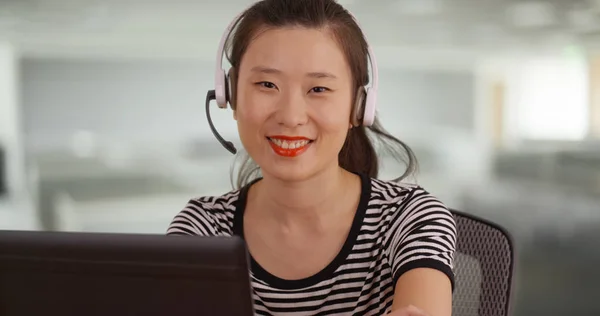 Millennial sales woman looking at camera with big smile at call center