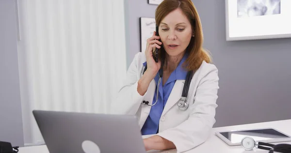 彼女は電話でチャット中にコンピューターを使用して素敵な女医の肖像画 — ストック写真